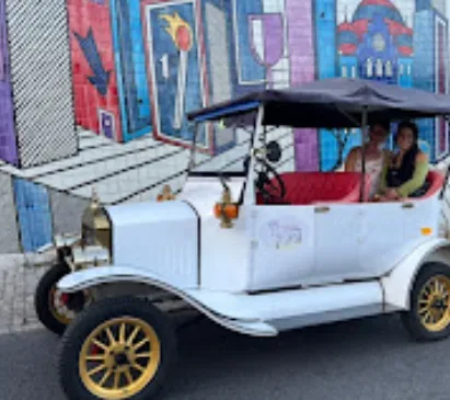 Vintage tuk tuk in front of a colorful Lisbon mural